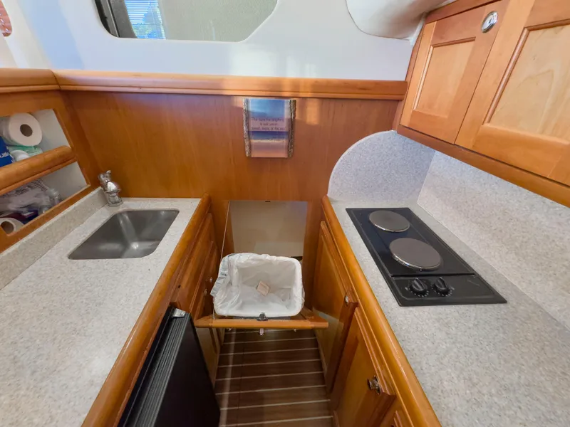 Slide: The Image of 2005 Mainship 34 Trawler kitchen with sink, stove, and wooden cabinetry. - 14