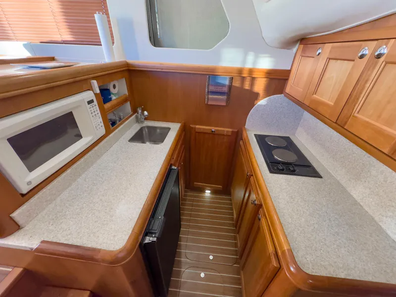 Slide: The Image of 2005 Mainship 34 Trawler galley with microwave, sink, stove, and wooden cabinetry. - 15