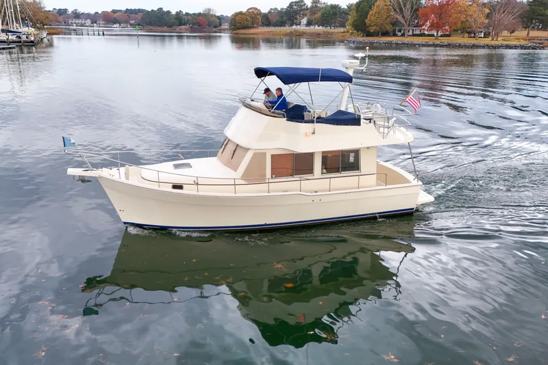 Slide: The Image of 2005 Mainship 34 Trawler cruising on a calm lake with autumn foliage. - 2