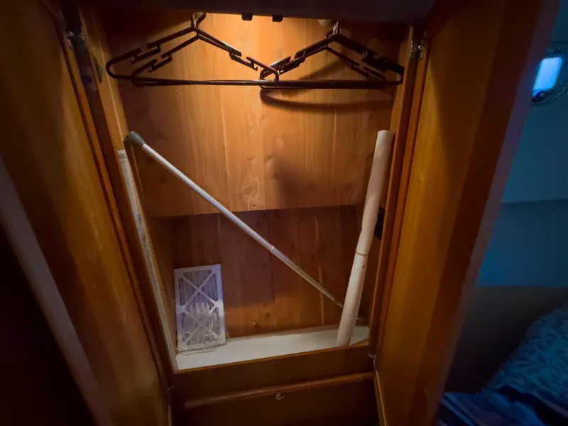 Slide: The Image of Wooden closet interior on 2005 Mainship 34 Trawler with hangers and cleaning tools. - 21