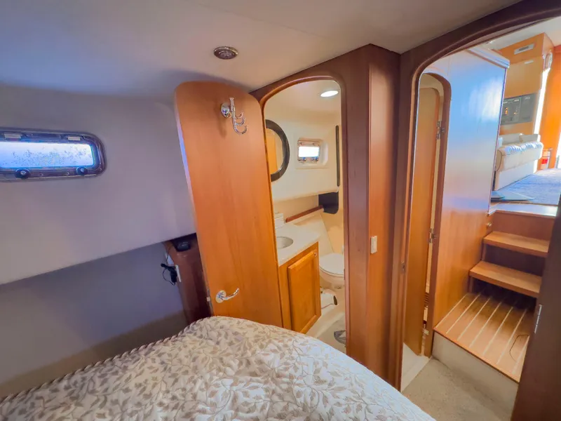 Slide: The Image of 2005 Mainship 34 Trawler interior with cozy bedroom, bathroom, and wooden stairs. - 23