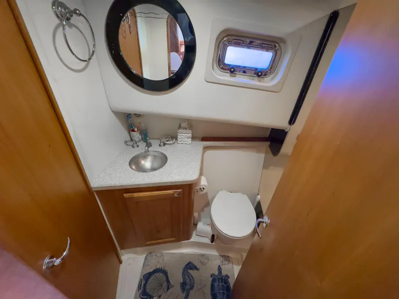 Slide: The Image of 2005 Mainship 34 Trawler bathroom with sink, mirror, and porthole window. - 25