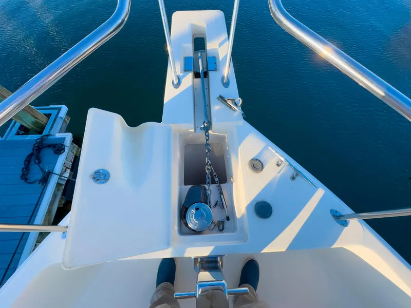Slide: The Image of Mainship 34 Trawler 2005 bow with anchor chain and railing, docked on calm water. - 34