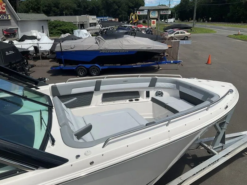 Slide: The Image of 2025 Chaparral 310 OSX boat on trailer at dealership, showcasing sleek design and spacious seating. - 12
