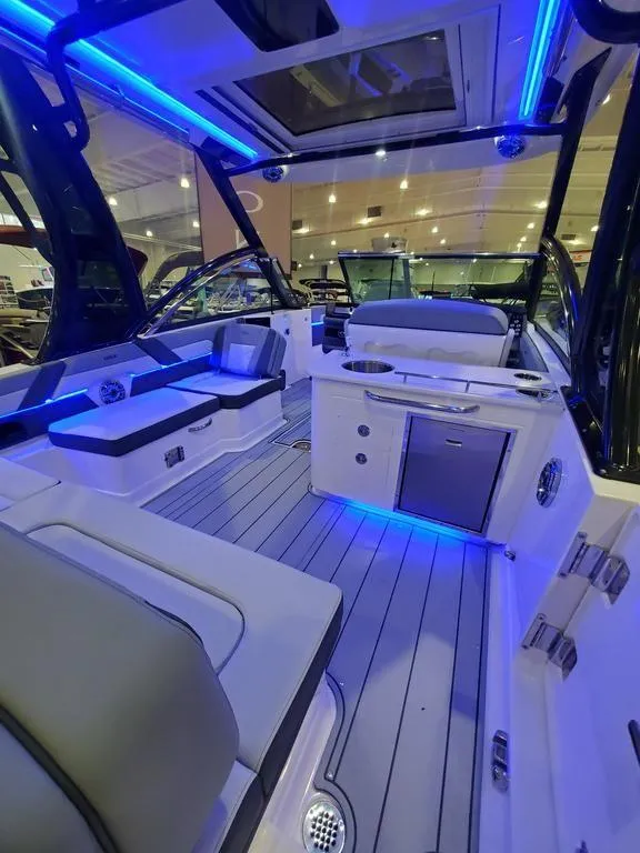 Slide: The Image of 2025 Chaparral 310 OSX boat interior with modern seating and blue LED lighting. - 13