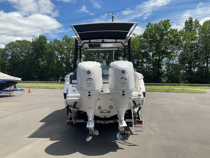 Slide: The Image of 2025 Chaparral 310 OSX boat with dual outboard engines, parked outdoors. - 16