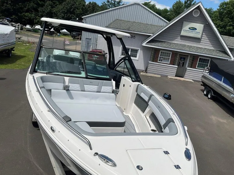 Slide: The Image of 2025 Chaparral 310 OSX boat displayed outside dealership, showcasing sleek design and spacious seating. - 19
