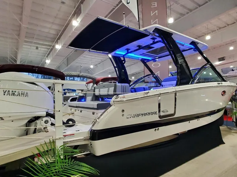 Slide: The Image of 2025 Chaparral 310 OSX boat with Yamaha engine, showcased indoors with blue LED lighting. - 23