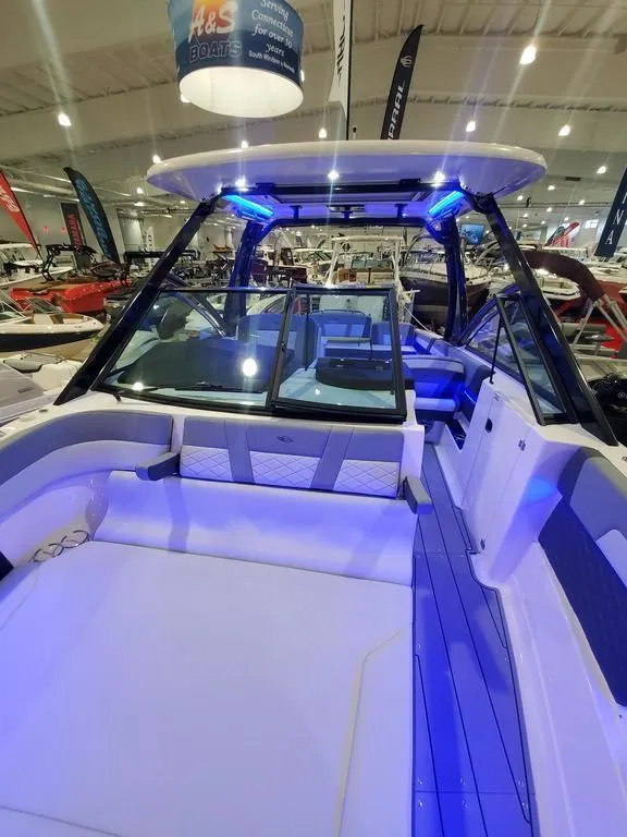 Slide: The Image of 2025 Chaparral 310 OSX boat interior with blue LED lighting at a showroom. - 25