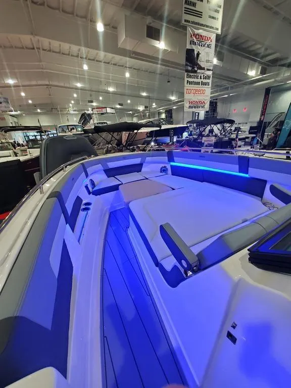 Slide: The Image of 2025 Chaparral 310 OSX boat interior with blue LED lighting at a showroom. - 26