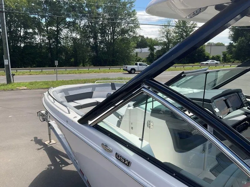 Slide: The Image of 2025 Chaparral 310 OSX boat with sleek design and modern cockpit, parked outdoors. - 28