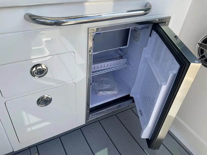Slide: The Image of Open refrigerator on 2025 Chaparral 310 OSX boat, showcasing storage space and sleek design. - 43