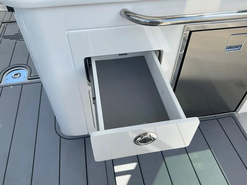 Slide: The Image of Open storage drawer on 2025 Chaparral 310 OSX boat, featuring sleek design and stainless steel handle. - 47