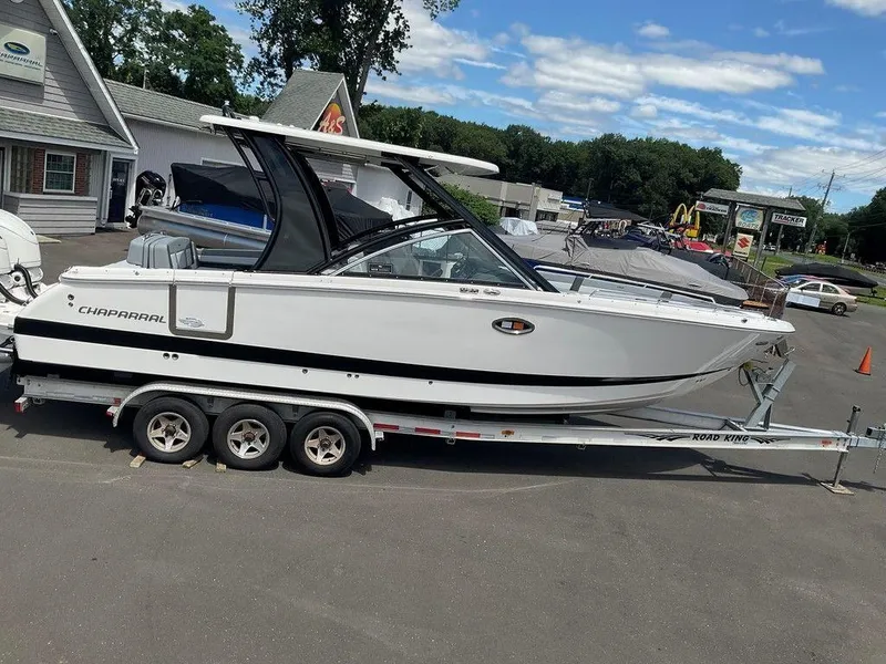 Slide: The Image of 2025 Chaparral 310 OSX boat on trailer, parked outdoors near dealership. - 5