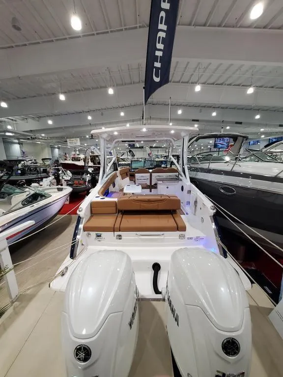 Slide: The Image of 2025 Chaparral 280 OSX boat displayed in a showroom with twin engines. - 2