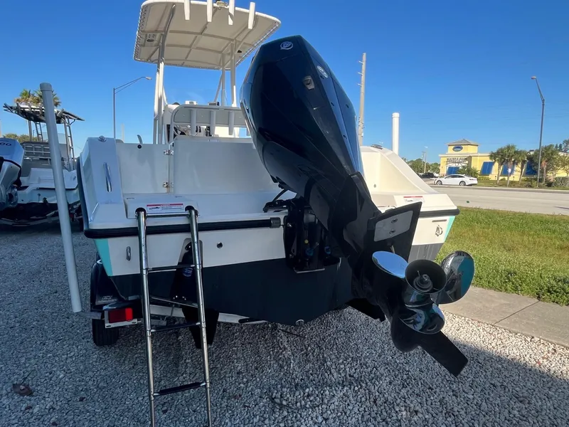 Slide: The Image of 2022 Cobia 237 Center Console boat with outboard motor and ladder, parked on gravel. - 8