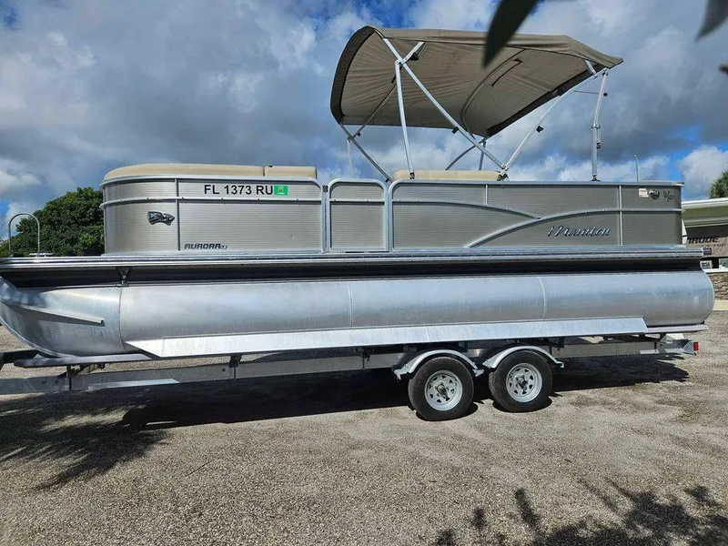 Slide: The Image of 2019 Manitou 22 Aurora LE 220VP Tritoon Pontoon on trailer, under blue sky. - 2