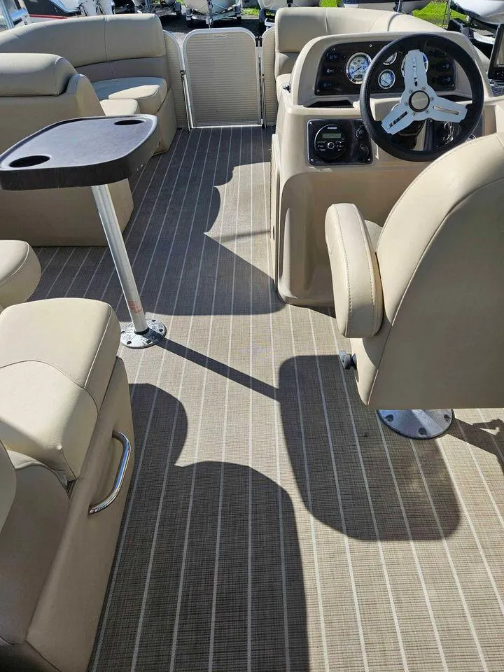 Slide: The Image of 2019 Manitou 22 Aurora LE 220VP Tritoon Pontoon interior with beige seating and steering console. - 4