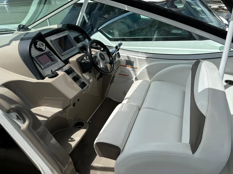 Slide: The Image of 2011 Cruisers Yachts 330 Express helm with white seating and modern dashboard controls. - 14