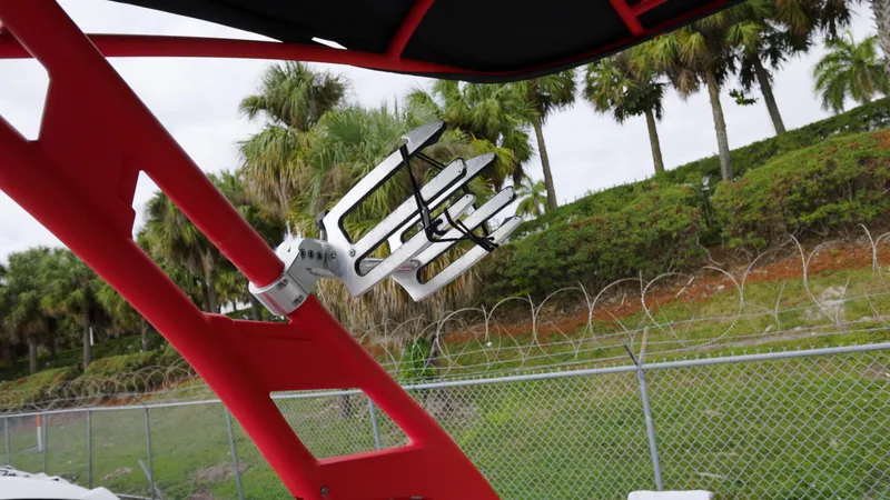 Slide: The Image of Red wakeboard rack on 2018 Yamaha Boats 242 XE, with palm trees in background. - 12