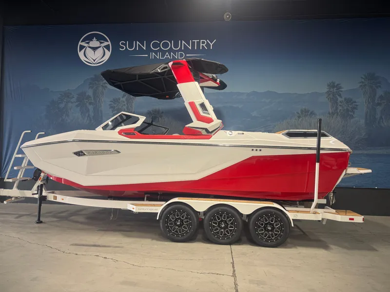 The Image of 2025 Nautique Super Air Nautique G23 Paragon boat in showroom, red and white design on trailer. - 1