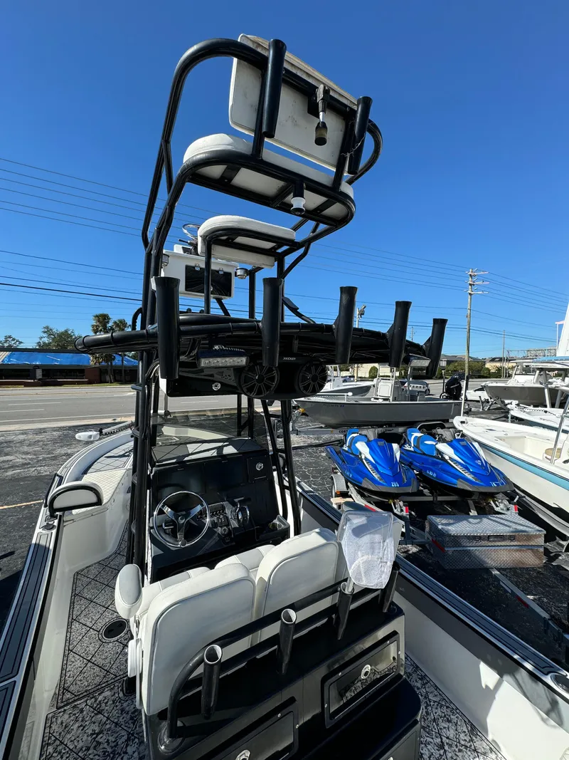 Slide: The Image of 2017 Action Craft 24 A.C.E. boat with elevated seating and rod holders, parked near jet skis. - 19