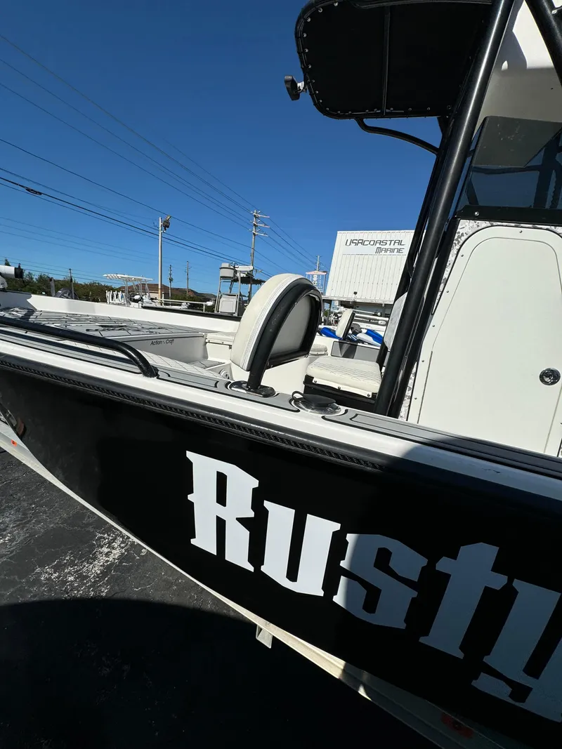 Slide: The Image of 2017 Action Craft 24 A.C.E. boat with "Rusty" lettering, parked outdoors. - 26