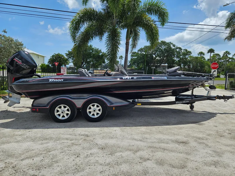 Slide: The Image of 2006 Triton Tr-21X HP boat on trailer, parked outdoors near greenery. - 2