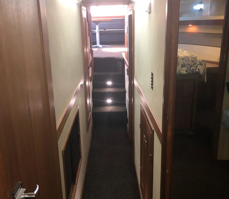 Slide: The Image of Hallway inside 1996 Bayliner 4788 Pilot House Motoryacht, featuring carpeted stairs and wooden paneling. - 35