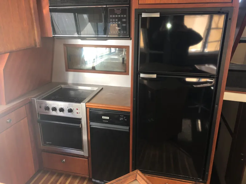 Slide: The Image of 1996 Bayliner 4788 Pilot House Motoryacht kitchen with stove, microwave, and refrigerator. - 9