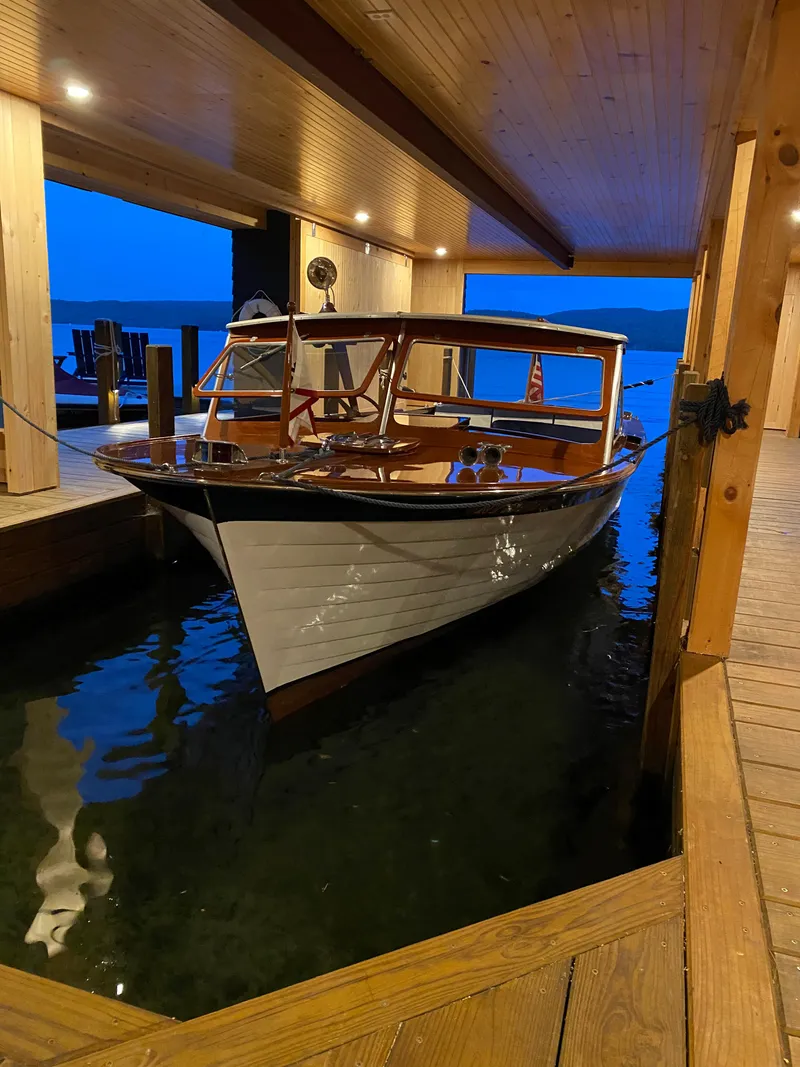 Slide: The Image of 1962 Lyman 24 Sleeper Hardtop boat docked in a wooden boathouse at dusk. - 10