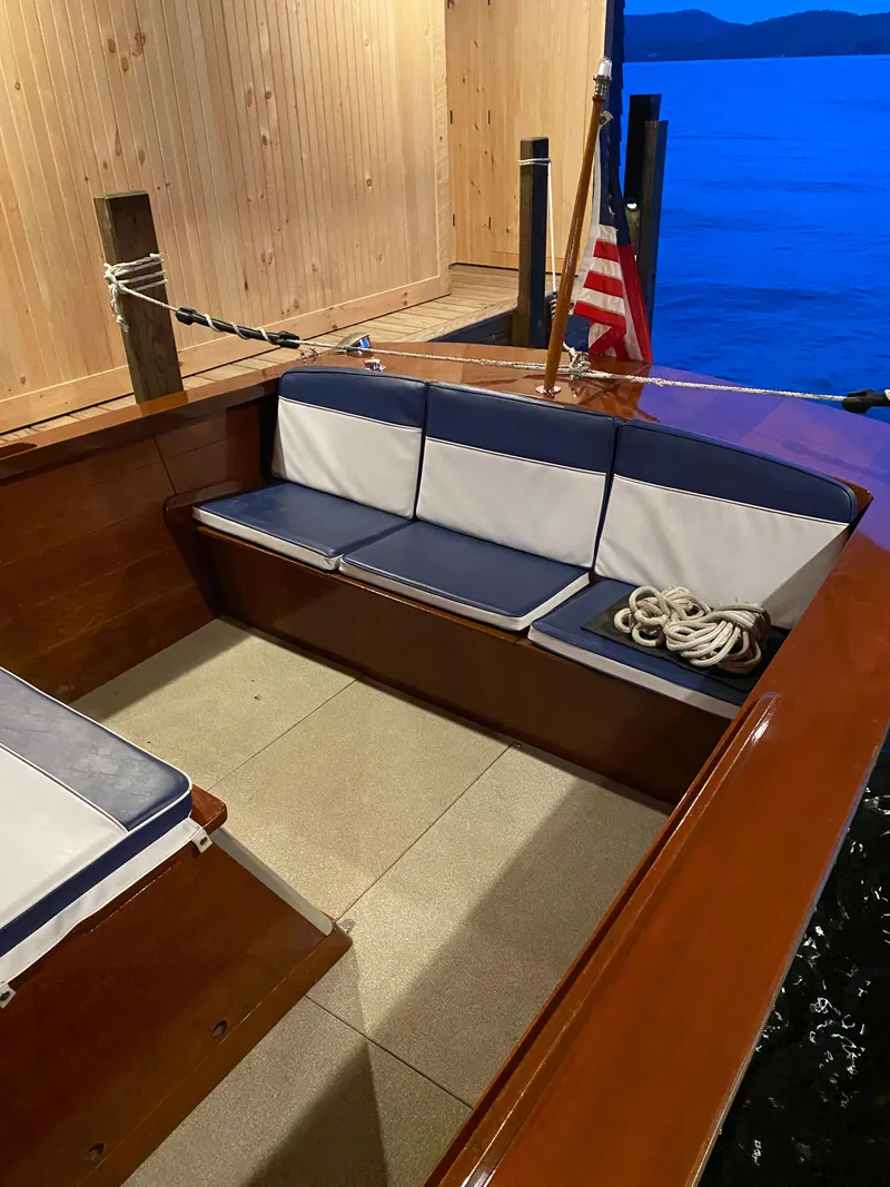 Slide: The Image of 1962 Lyman 24 Sleeper Hardtop boat interior with blue and white seating, docked by calm water. - 14