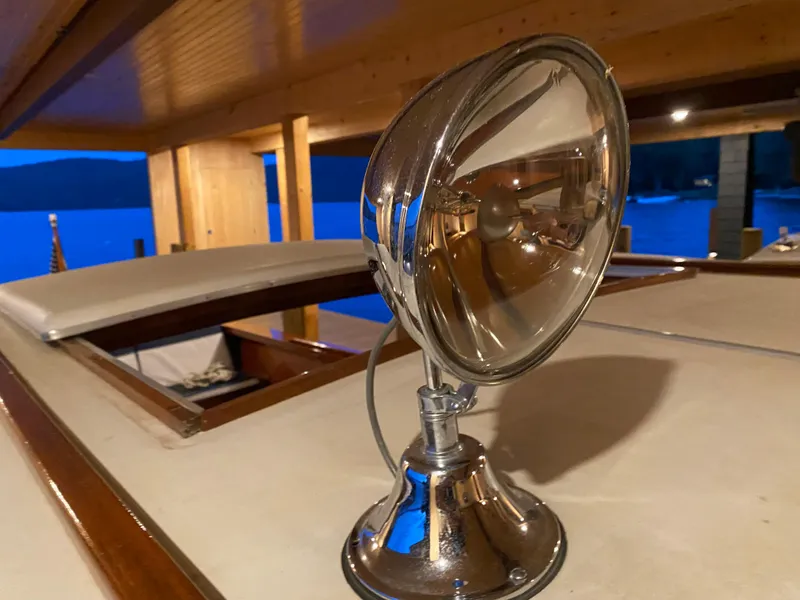 Slide: The Image of 1962 Lyman 24 Sleeper Hardtop spotlight on deck at dusk by the water. - 18