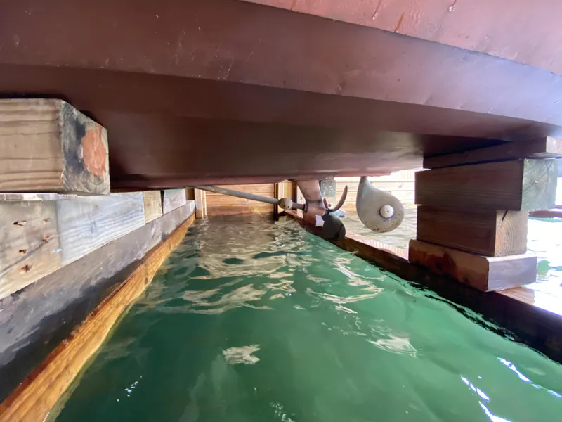 Slide: The Image of Underneath view of a 1962 Lyman 24 Sleeper Hardtop boat in a wooden dock. - 29