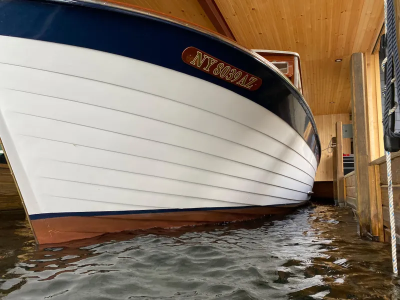 Slide: The Image of 1962 Lyman 24 Sleeper Hardtop boat docked in a wooden boathouse. - 5