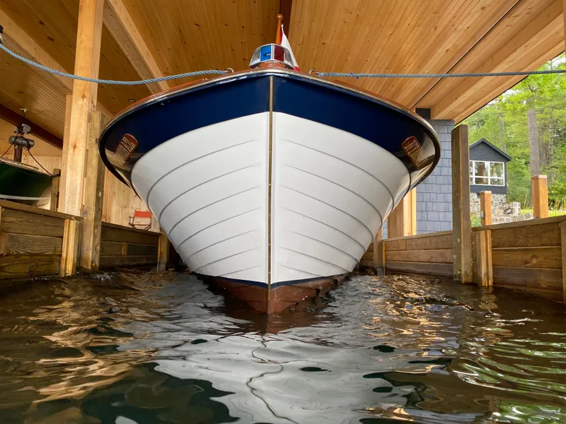 Slide: The Image of 1962 Lyman 24 Sleeper Hardtop boat docked in a wooden boathouse. - 6