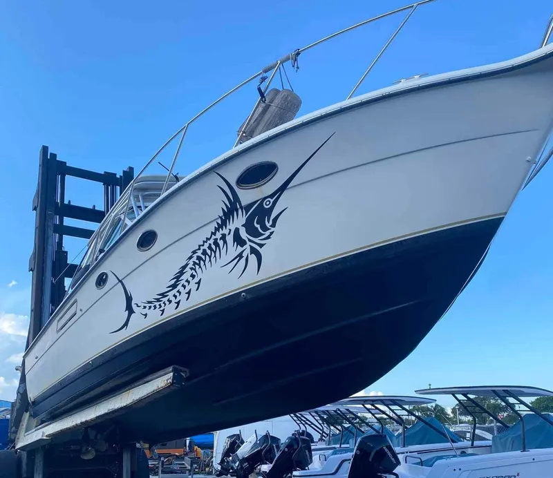 Slide: The Image of 1995 Tiara Yachts 3100 Open with marlin decal, docked under clear blue sky. - 7