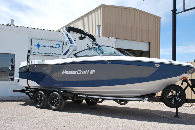 Slide: The Image of 2024 MasterCraft XT24 boat on trailer, parked outside a building. - 1