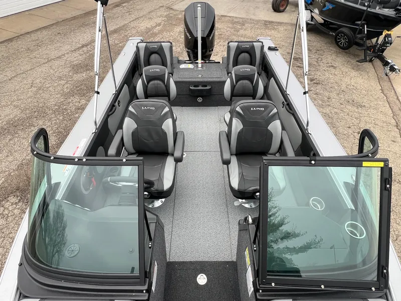 Slide: The Image of 2025 Lund 1975 Tyee boat interior with seating and windshield, parked on pavement. - 17