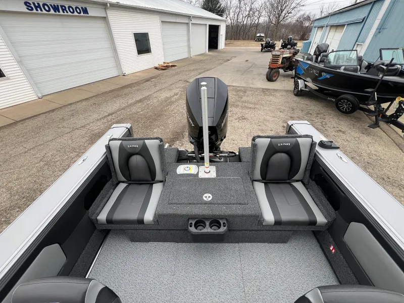Slide: The Image of 2025 Lund 1975 Tyee boat interior at showroom, featuring modern seating and motor. - 34