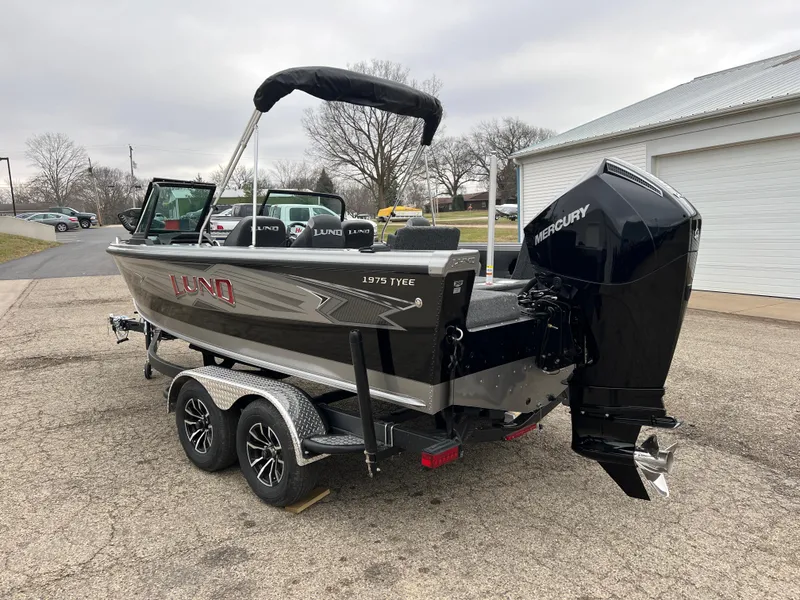 Slide: The Image of 2025 Lund 1975 Tyee boat with Mercury engine on trailer, parked outdoors. - 4