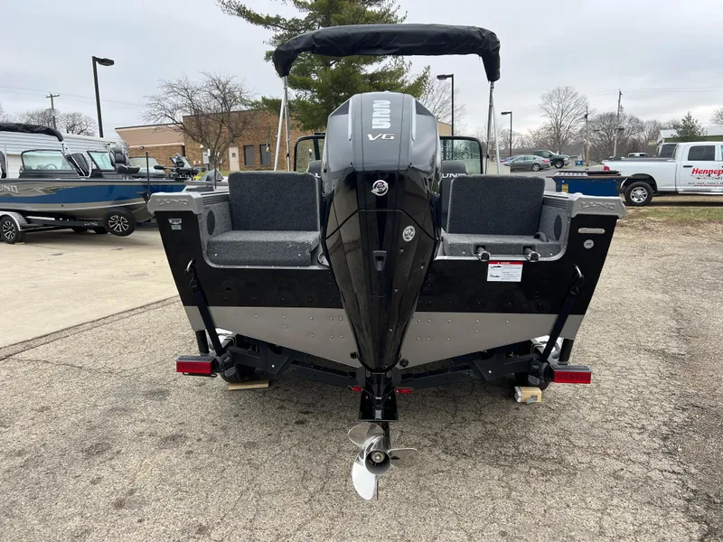 Slide: The Image of 2025 Lund 1975 Tyee boat, rear view with outboard motor, parked outdoors. - 5
