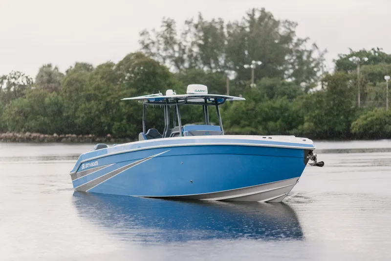 Slide: The Image of Blue AMP 333 boat from 2021 on calm water with trees in the background. - 2
