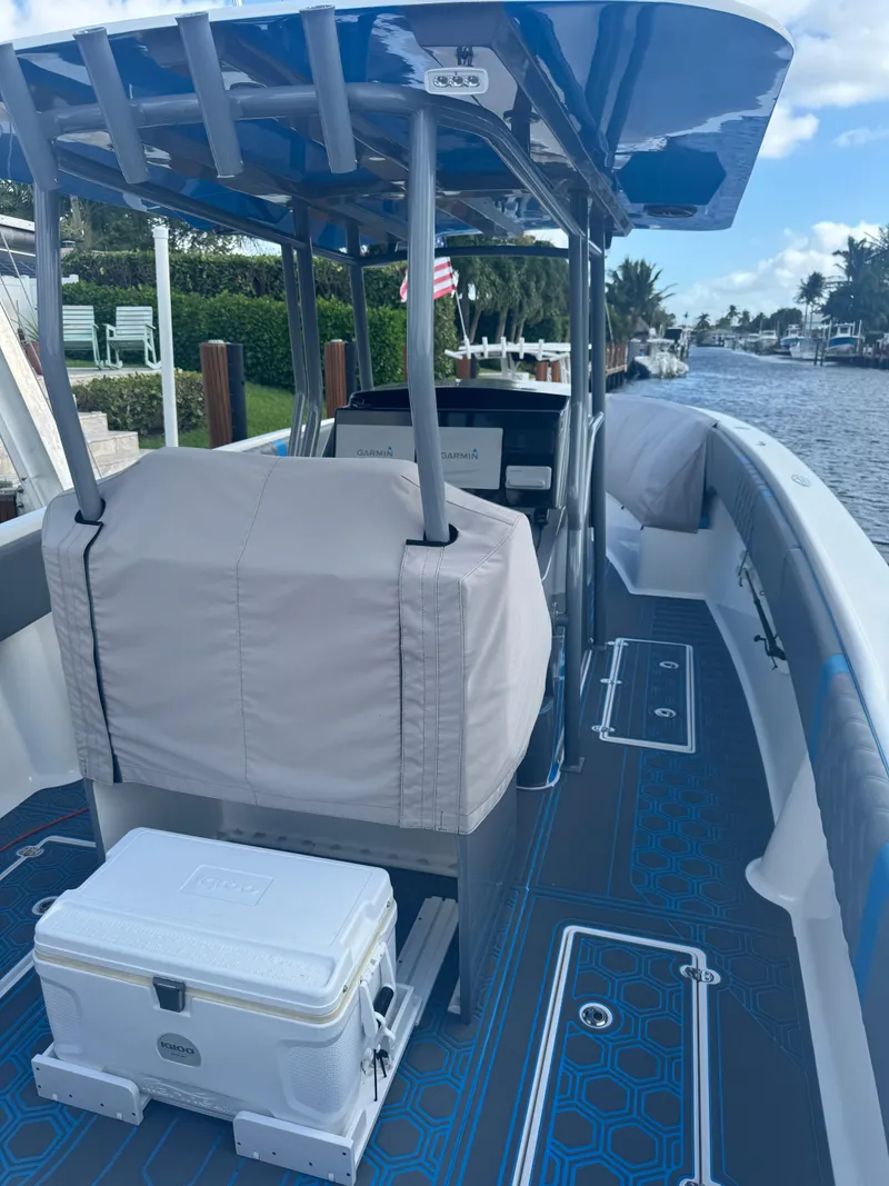 Slide: The Image of AMP 333 boat, 2021 model, with covered seating and cooler on deck, docked by a canal. - 5