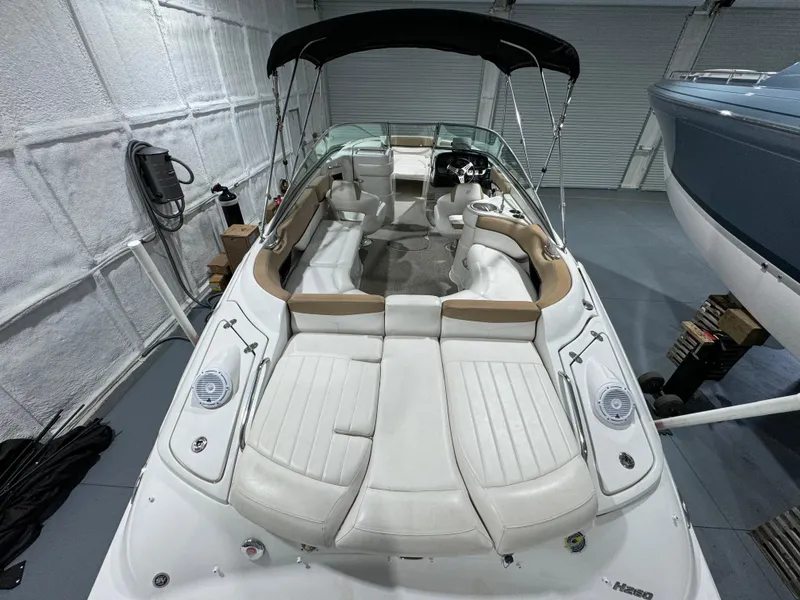 Slide: The Image of 2012 Four Winns H260 boat with white seating and black canopy in a garage. - 8