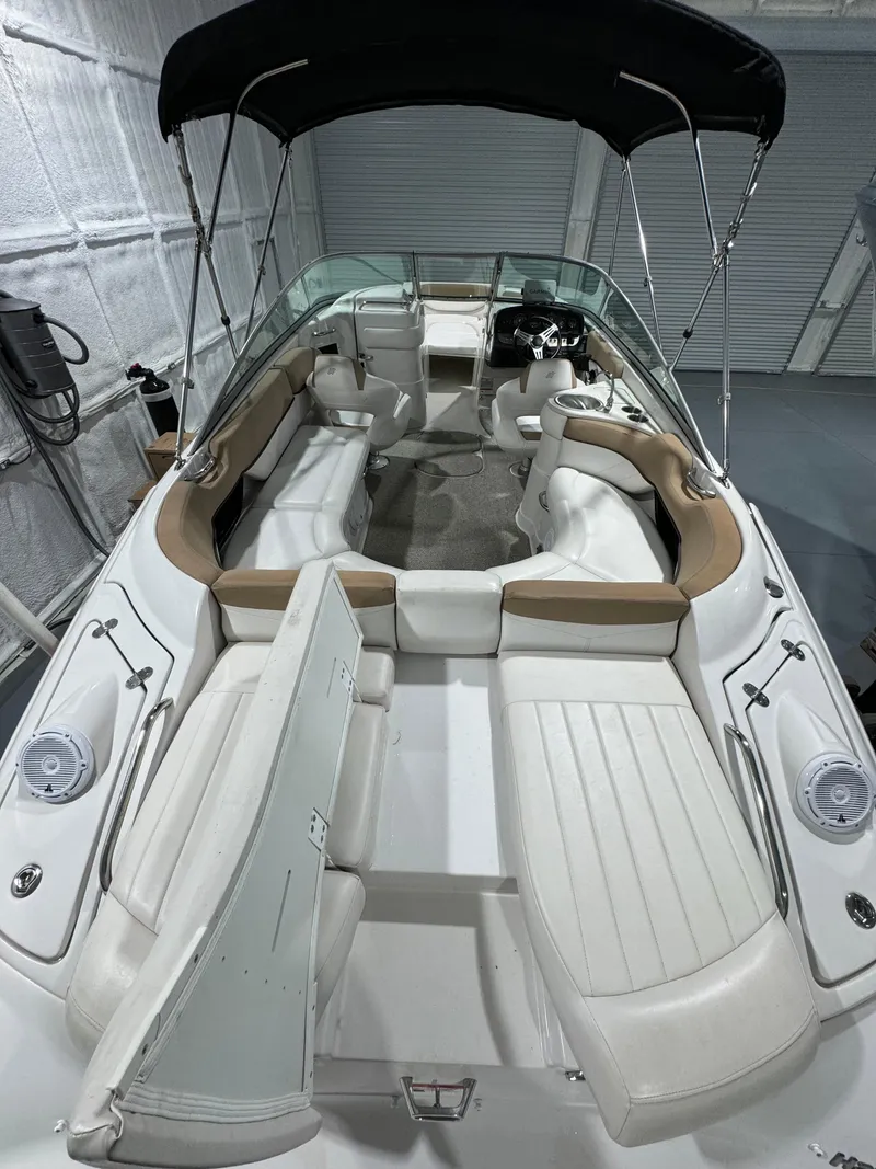 Slide: The Image of 2012 Four Winns H260 boat with spacious seating and canopy in a storage facility. - 9