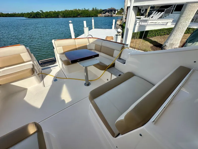 Slide: The Image of 2012 Tiara Yachts 3100 Coronet with spacious seating and table, docked by serene waters. - 17