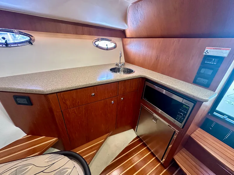 Slide: The Image of 2012 Tiara Yachts 3100 Coronet interior with kitchenette, sink, and wood cabinetry. - 27