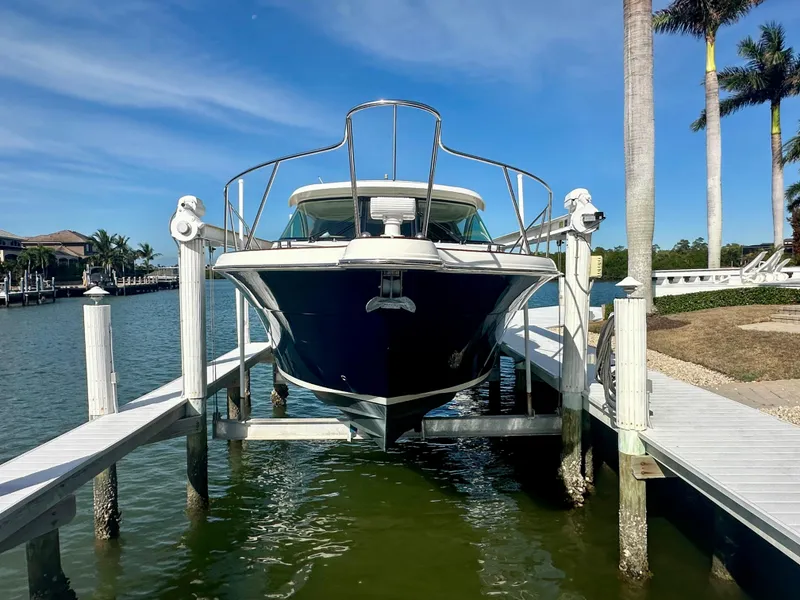 Slide: The Image of 2012 Tiara Yachts 3100 Coronet docked on a lift, surrounded by palm trees. - 3