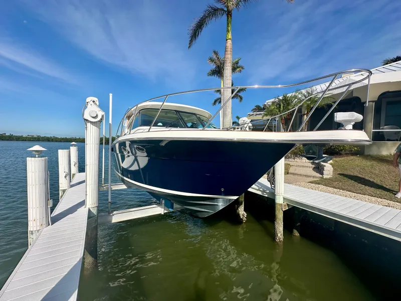 Slide: The Image of 2012 Tiara Yachts 3100 Coronet on lift, docked by waterfront home. - 4